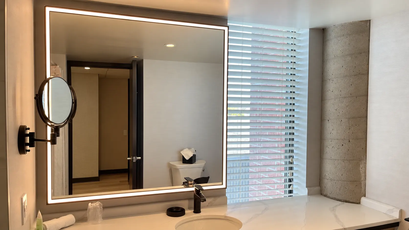 Wall mounted makeup mirror installed in a hotel bathroom